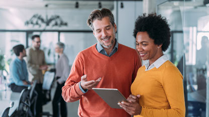 Des professionnels en affaires discutant dans un bureau tout en tenant une tablette.